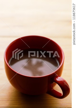 Cup of delicious hot chocolate with red maple leaf reflection on wooden table background. Selective focus. Cup of delicious hot chocolate with red maple leaf reflection on wooden table background. Selective focus. 118675617