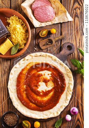 Raw pizza dough with tomato sauce and basil leaves. Raw pizza dough with tomato sauce and basil leaves. 118676022