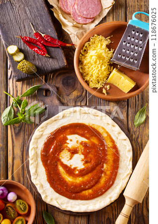 Raw pizza dough with tomato sauce and basil leaves. 118676025