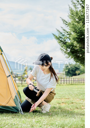 Woman assembling a tent Woman assembling a tent 118677267