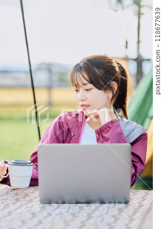 A woman working remotely at a campsite 118677639