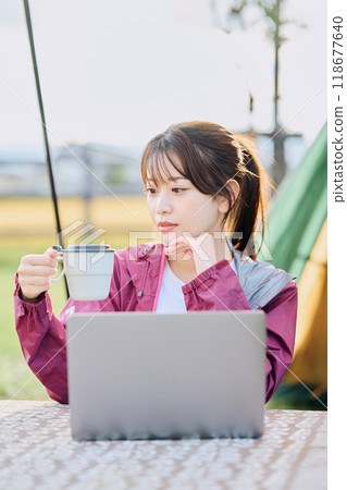 A woman working remotely at a campsite 118677640