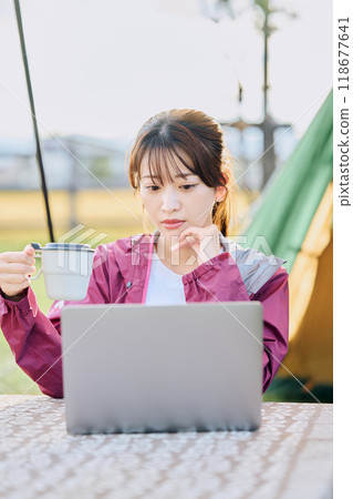 A woman working remotely at a campsite A woman working remotely at a campsite 118677641