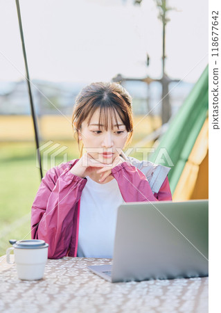 A woman working remotely at a campsite A woman working remotely at a campsite 118677642