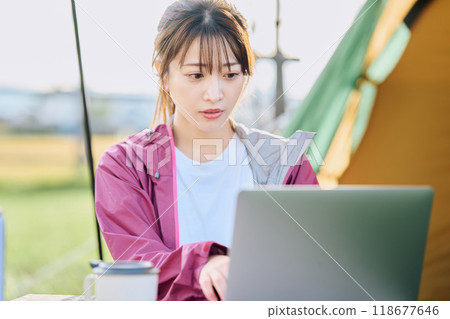 A woman working remotely at a campsite A woman working remotely at a campsite 118677646