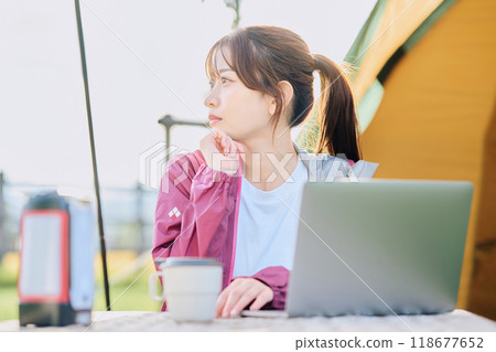 A woman working remotely at a campsite A woman working remotely at a campsite 118677652