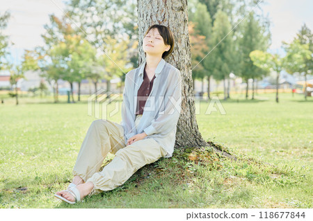 Woman sitting on the grass in the park Woman sitting on the grass in the park 118677844