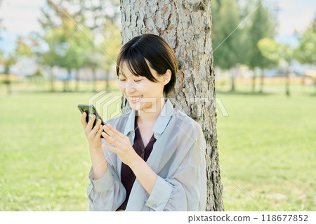 A woman using a smartphone in a park A woman using a smartphone in a park 118677852