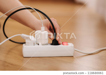Woman plugging the wire into white extension cord. Close up of female hand put cable Woman plugging the wire into white extension cord. Close up of female hand put cable 118680061