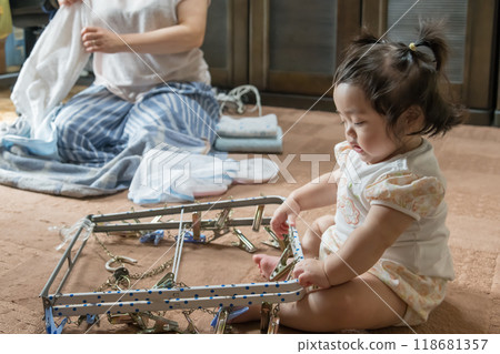 [Baby with twin tails touching a laundry hanger] 118681357