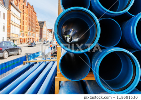 Close-up blue PVC plumbing pipes stacked wooden pallets replacement at german city street infrastructure construction site. Town development building industrial background 118681530