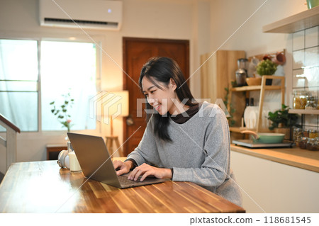 Charming young asian woman using laptop on kitchen counter at home Charming young asian woman using laptop on kitchen counter at home 118681545