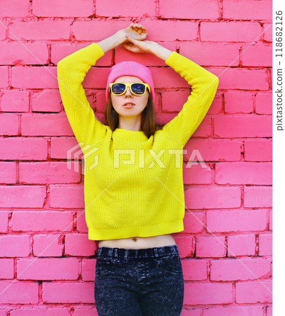 Portrait stylish young teenager girl in vivid colorful clothes, knitted yellow sweater and pink hat Portrait stylish young teenager girl in vivid colorful clothes, knitted yellow sweater and pink hat 118682126