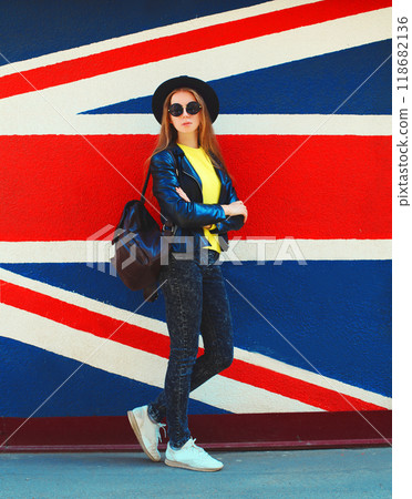Portrait of beautiful young woman posing on english flag wall background 118682136