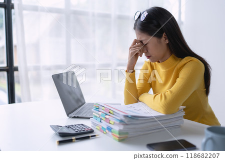 businesswoman plans a finance audit, reviewing documents while battling burnout syndrome. 118682207