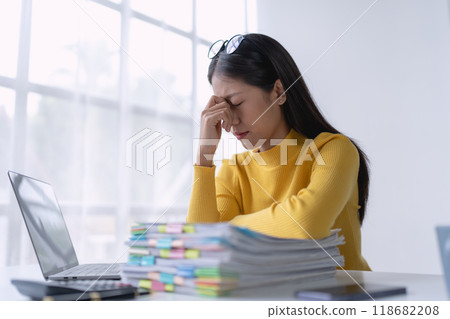 businesswoman plans a finance audit, reviewing documents while battling burnout syndrome. 118682208