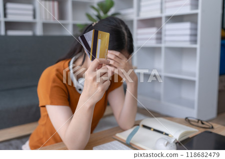 woman feels stressed as she grapples with credit debt, overwhelmed by the financial burden and struggling to find a solution to her challenging situation 118682479