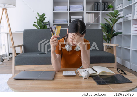 woman feels stressed as she grapples with credit debt, overwhelmed by the financial burden and struggling to find a solution to her challenging situation 118682480