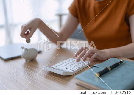 woman creates a detailed financial saving plan using a calculator to organize her expenses and ensure long-term financial stability and security 118682510