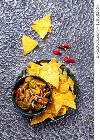 Single big black plate of yellow corn tortilla nachos chips with salsa sauce Single big black plate of yellow corn tortilla nachos chips with salsa sauce 118682657