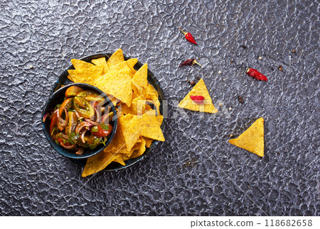 Single big black plate of yellow corn tortilla nachos chips with salsa sauce Single big black plate of yellow corn tortilla nachos chips with salsa sauce 118682658