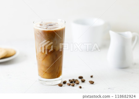 Ice coffee in a tall glass with milk on white marble table. 118682924
