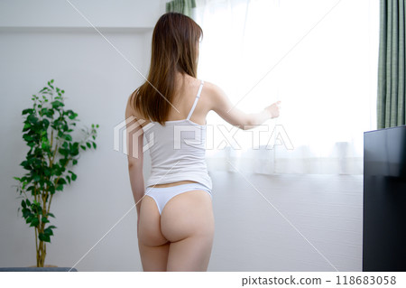 A young, slender woman in underwear with a beautiful back view basking in the morning sun 118683058