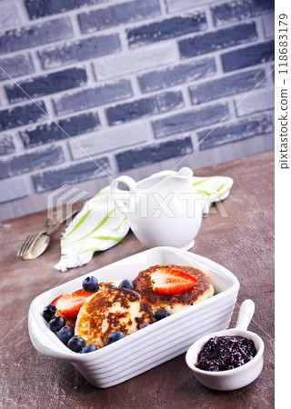 Cottage cheese pancakes or syrniki with sour cream, honey and berries. 118683179