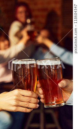 Cheers to game. Friends gather, drinks in hand, while background buzzes with energy. Bar atmosphere captures perfect sports celebration. Cheers to game. Friends gather, drinks in hand, while background buzzes with energy. Bar atmosphere captures perfect sports celebration. 118684347