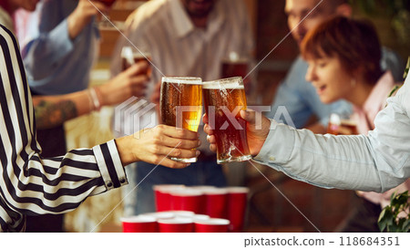 Cheers fill room, beer cups in hand, as game intensifies. Blurred background reveals lively group of sport enthusiasts enjoying competition. Cheers fill room, beer cups in hand, as game intensifies. Blurred background reveals lively group of sport enthusiasts enjoying competition. 118684351