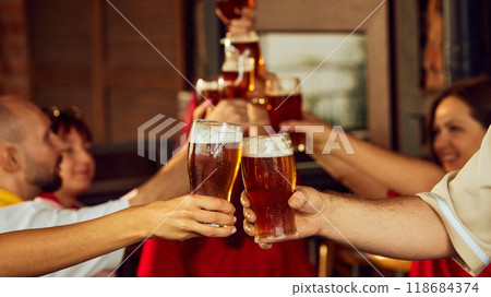 Beers held high in toast of triumph. Background fades into a blur, keeping focus on emotions shared among fans. Beers held high in toast of triumph. Background fades into a blur, keeping focus on emotions shared among fans. 118684374