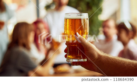Clinking glasses, full of energy and emotion, sport fans toast to their team's win. Moment golden, just like drinks they hold. 118684390