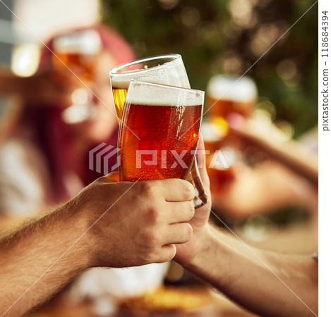 Dynamic toast among sport fans, glasses brimming with beer. Background blur emphasizes shared excitement. Selective focus. 118684394