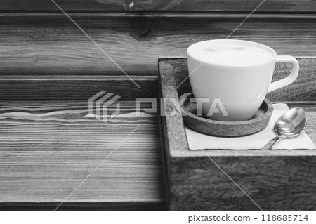 White coffee cup with spoon on wooden tray, black and white. Americano with milk on serving tray, monochrome. Coffee break concept. Served hot drink in restaurant. Coffee table close up. Hot drinks White coffee cup with spoon on wooden tray, black and white. Americano with milk on serving tray, monochrome. Coffee break concept. Served hot drink in restaurant. Coffee table close up. Hot drinks 118685714