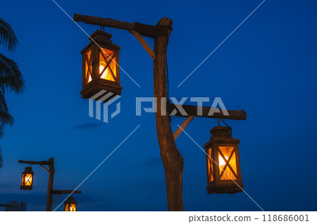 An old street lamp on a lamppost illuminating a dark street An old street lamp on a lamppost illuminating a dark street 118686001