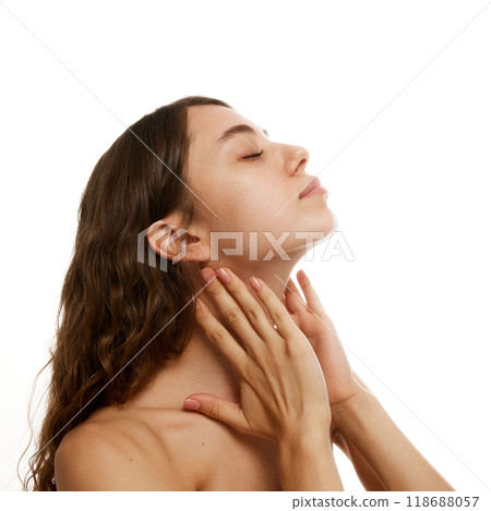 Young, attractive woman softly massaging her neck, illustrating relaxation and wellness against white studio background. 118688057