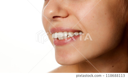 Detailed photo. Side profile of smile, focusing on natural lips and healthy teeth, part of beauty and facial care against a white studio background. 118688113