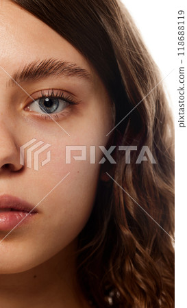 Half face portrait with soft expression, emphasizing clear skin and natural beauty care against white studio background. 118688119