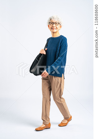 Full body photo of a senior woman walking with a bag 118688600