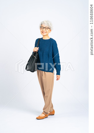 Full body photo of a senior woman walking with a bag 118688604