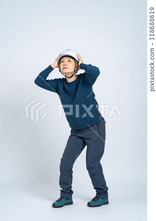 Full body photo of a senior woman protecting her head with a helmet 118688619