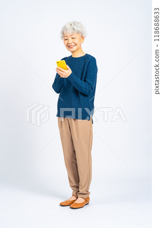 一位高級女性微笑著使用智慧型手機的全身照片 一位高級女性微笑著使用智慧型手機的全身照片 118688633