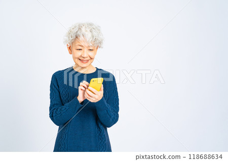 一位高級女性微笑著使用智慧型手機 一位高級女性微笑著使用智慧型手機 118688634