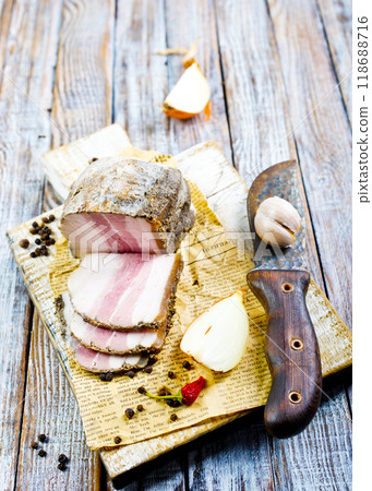 Smoked lard, bacon, half a piece, on a wooden dark craft board. Top view, close-up. 118688716