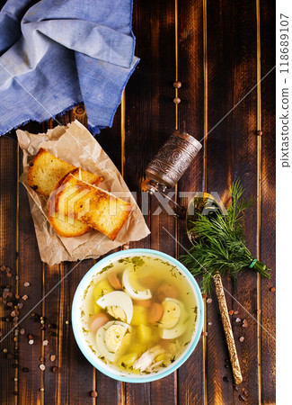 Egg drop soup with meat in white porcelain bowl on wooden table. Fresh soup with eggs and vegetable 118689107