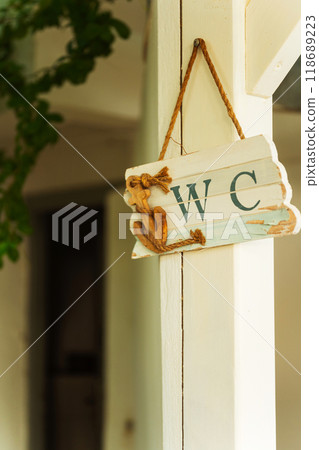 A wooden sign hanging from a tree that says wc  118689223