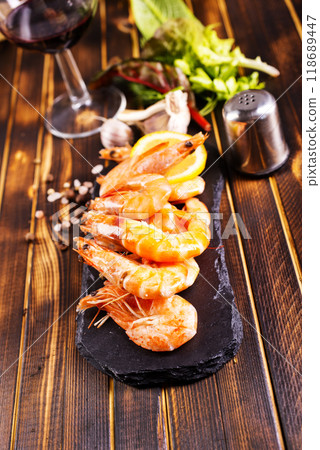 Fried shrimps with garlic, lemon served on black plate on wooden table 118689447