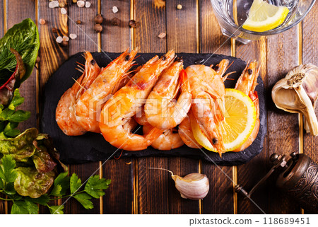 Fried shrimps with garlic, lemon served on black plate on wooden table Fried shrimps with garlic, lemon served on black plate on wooden table 118689451