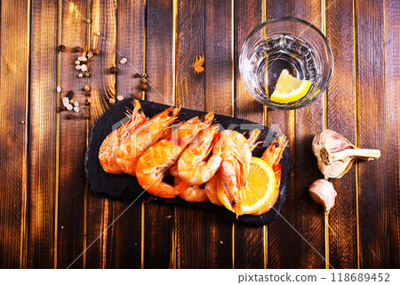 Fried shrimps with garlic, lemon served on black plate on wooden table Fried shrimps with garlic, lemon served on black plate on wooden table 118689452