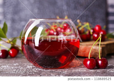 Cherry juice in a glass and fresh cherries on a table 118689525